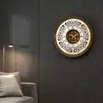 Add a touch of timeless elegance to your living space with this exquisite Round Unique Gold Patina Wall Clock. The intricate frame boasts a royal vintage effect, creating a luxurious atmosphere in any room. The mirrored design adds a touch of glamour, while the boho style clock enhances the overall aesthetic. Perfect for a chic living room, bedroom, or office, this stunning piece of wall art effortlessly combines style and functionality. Make a statement with this one-of-a-kind wall clock that will surely elevate your decor.