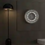 Add a touch of timeless elegance to your living room with this Roman Numeral Wall Clock. This unique wall art piece boasts a chic vintage look with its round design and silver patina finish. Its sophisticated appeal makes it the perfect addition to any stylish space, adding an elegant touch to your decor. Make a statement in your living room with this exquisite clock that is sure to impress your guests and elevate your room decor.