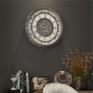 Add a touch of timeless elegance to your living room with this Roman Numeral Wall Clock. This unique wall art piece boasts a chic vintage look with its round design and silver patina finish. Its sophisticated appeal makes it the perfect addition to any stylish space, adding an elegant touch to your decor. Make a statement in your living room with this exquisite clock that is sure to impress your guests and elevate your room decor.