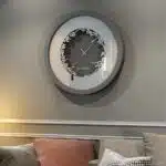 Add a touch of elegance to your space with this traditional round-shaped handmade wall clock adorned with 5 stunning surrounding colors - black, gray, gold, beige, and walnut. The captivating design feature of this piece is the intricate Persian calligraphy encircling the mirrored clock, creating a stylish one-of-a-kind look that shines beautifully on any wall. This large modern wall clock is not only a functional timepiece but also a stunning piece of art. With its oversized silhouette and silent mechanism, it is perfect for adding a bold statement to your kitchen or any room in your home. Make a stylish statement with this unique and eye-catching timepiece.