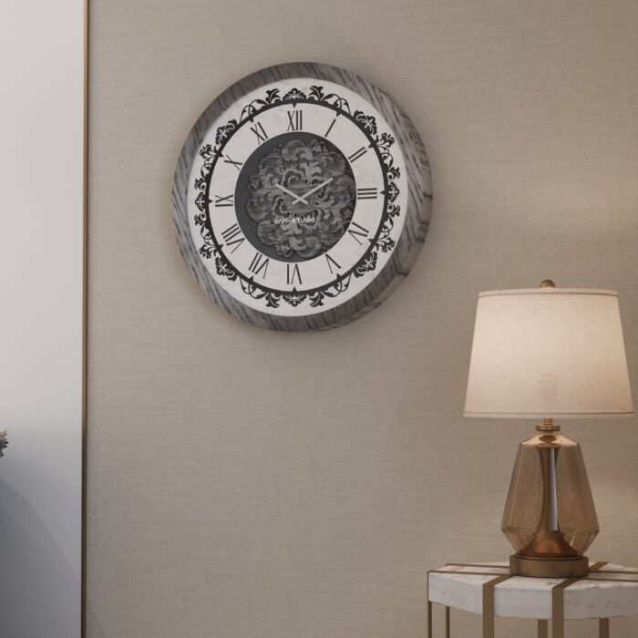 Add a touch of timeless elegance to your living room with this Roman Numeral Wall Clock. This unique wall art piece boasts a chic vintage look with its round design and silver patina finish. Its sophisticated appeal makes it the perfect addition to any stylish space, adding an elegant touch to your decor. Make a statement in your living room with this exquisite clock that is sure to impress your guests and elevate your room decor.