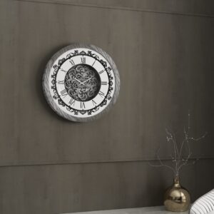 Add a touch of timeless elegance to your living room with this Roman Numeral Wall Clock. This unique wall art piece boasts a chic vintage look with its round design and silver patina finish. Its sophisticated appeal makes it the perfect addition to any stylish space, adding an elegant touch to your decor. Make a statement in your living room with this exquisite clock that is sure to impress your guests and elevate your room decor.