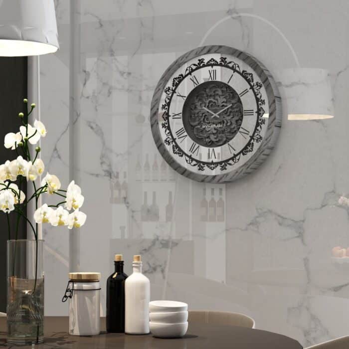 Add a touch of timeless elegance to your living room with this Roman Numeral Wall Clock. This unique wall art piece boasts a chic vintage look with its round design and silver patina finish. Its sophisticated appeal makes it the perfect addition to any stylish space, adding an elegant touch to your decor. Make a statement in your living room with this exquisite clock that is sure to impress your guests and elevate your room decor.