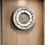 Add a touch of timeless elegance to your living room with this Roman Numeral Wall Clock. This unique wall art piece boasts a chic vintage look with its round design and silver patina finish. Its sophisticated appeal makes it the perfect addition to any stylish space, adding an elegant touch to your decor. Make a statement in your living room with this exquisite clock that is sure to impress your guests and elevate your room decor.
