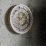 Handmade round Roman numeral wall clock with beige wooden frame and patina floral mirror design