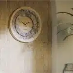 Handmade round Roman numeral wall clock with beige wooden frame and patina floral mirror design