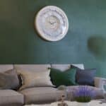 Handmade round Roman numeral wall clock with beige wooden frame and patina floral mirror design