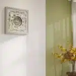 Square oversized wall clock with a silver wooden frame, mirrored glass face, Roman numerals, and floral wood center.