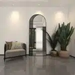 Add a touch of contemporary elegance to your living space with this Modern Arched Floor Mirror. This full-length lean wall mirror features an asymmetrical design, perfect for adding a chic flair to your housewarming decor. Use it as a leaner mirror in your bedroom or living room to create the illusion of a larger space while adding a stylish statement piece. Elevate your home decor with this stunning and sleek large mirror that will instantly upgrade any room in your house.