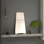 Elevate your space with this stunning Wavy Asymmetrical Gold Wall Mirror. This modern chic home decor piece is perfect for adding a touch of elegance to your bathroom vanity or living room. The irregular shape of the mirror creates a unique and eye-catching design element, setting it apart from traditional mirrors. Bring a touch of luxury to your home with this elegant vanity aesthetic that will surely enhance any room's aesthetic.