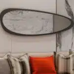Add a touch of modern elegance to your space with this Mid Century Asymmetrical Black Mirror. This striking piece features an irregular design, making it a unique addition to any room. Whether used as a bathroom vanity mirror or as stylish living room décor, this large wall mirror is sure to make a statement. Perfect for her, this mirror also makes a thoughtful housewarming gift for that special someone who loves contemporary style. Elevate your decor with this one-of-a-kind piece that combines functionality with fashion.