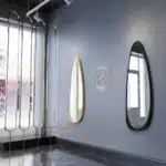 Elevate your space with this stunning Mid Century Asymmetrical Black Mirror. This Irregular Bathroom Vanity Mirror is the perfect addition to any stylish Living Room Décor. The large size makes it ideal as a statement piece or as a practical Housewarming Gift for her. Add a touch of sophistication to your home with this unique and modern wall mirror.