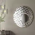 Add a touch of elegance and style to your space with this Round Asymmetrical Mirror. Perfect for your living room decor or as a statement piece in your bathroom, this large circle wall mirror will bring a unique accent to any room. The decorative sunburst style adds a modern flair while also incorporating a classic design. Elevate your home decor with this stunning mirror that will surely catch the eye of all your guests.
