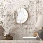 Small round wall mirror with an etched Persian calligraphy design featuring the words 'Women, Life, Freedom,' framed in a gold and black color scheme, hanging on a wall.