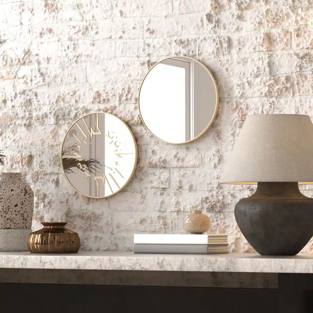 Small round wall mirror with an etched Persian calligraphy design featuring the words 'Women, Life, Freedom,' framed in a gold and black color scheme, hanging on a wall.