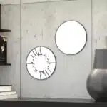 Small round wall mirror with an etched Persian calligraphy design featuring the words 'Women, Life, Freedom,' framed in a gold and black color scheme, hanging on a wall.