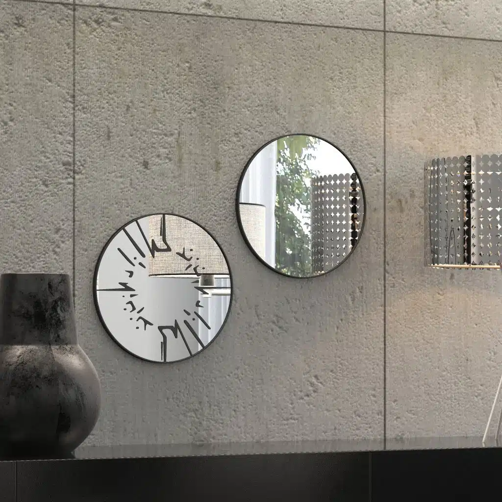 Small round wall mirror with an etched Persian calligraphy design featuring the words 'Women, Life, Freedom,' framed in a gold and black color scheme, hanging on a wall.