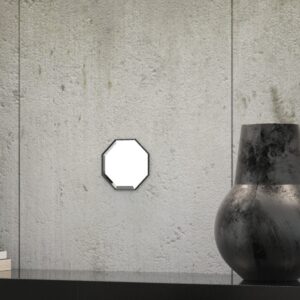 A octagonal wall mirror elegantly mounted on a wall adjacent to a well-stocked bookshelf, enhancing the room's aesthetic appeal.