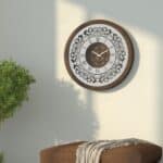 Handmade round wall clock with a wooden frame in walnut patina, mirrored glass front featuring Roman numerals, and a floral carved wood center, perfect for elegant home decor.