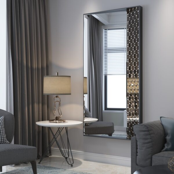 tylish decorative wall mirror with a unique geometric design on one side, framed in a modern, sleek border. Placed in an elegant living room setting with neutral tones, the mirror reflects natural light, adding depth and sophistication to the space. The room features a comfortable gray chair with a checkered cushion, a modern side table with a sculptural lamp, and a cozy sofa, creating a contemporary yet warm atmosphere.