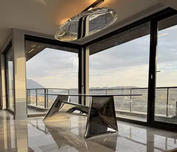 Sleek metallic modern table and chrome light fixture in a luxury room with a view.