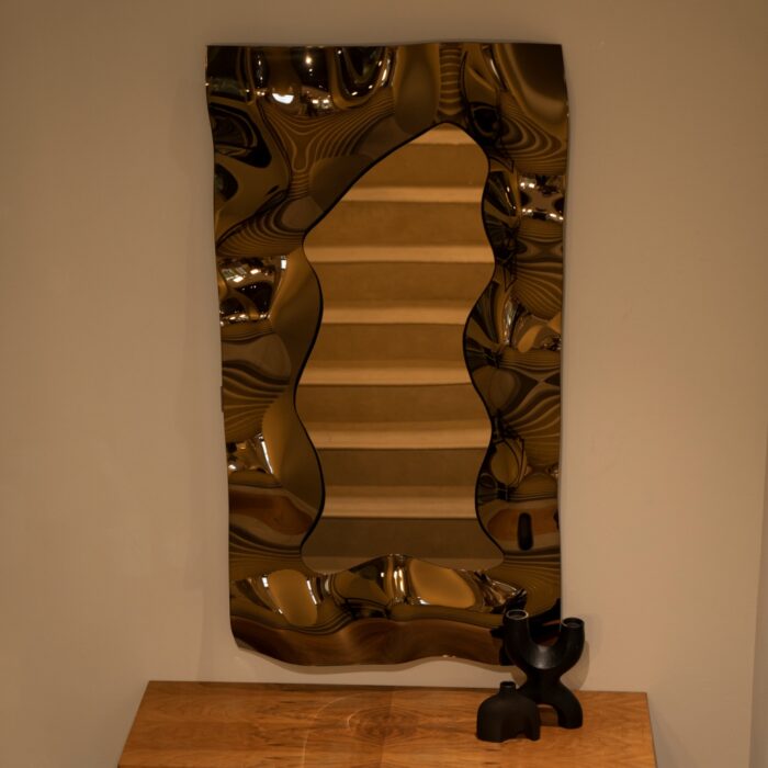 A sophisticated bronze glass mirror with a sculptural wave design