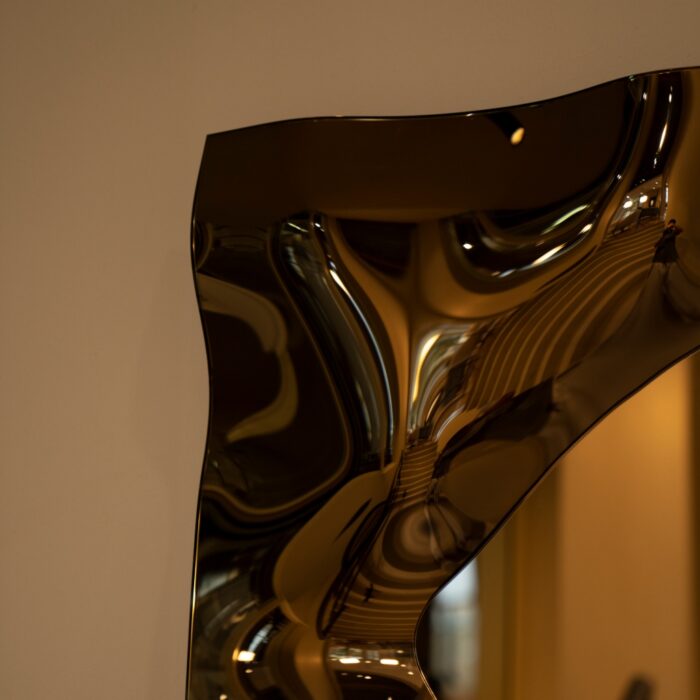 A sophisticated bronze glass mirror with a sculptural wave design