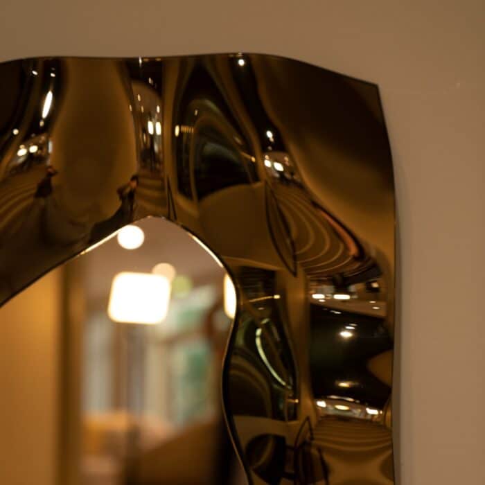 A sophisticated bronze glass mirror with a sculptural wave design